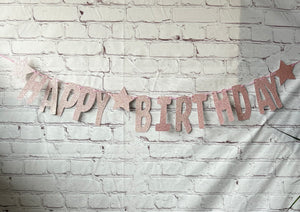 Happy Birthday banner with pink glitter on a white brick wall background